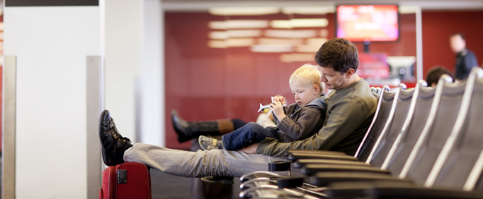 Traveling With Children AAA - Father and son waiting and playing at the airport