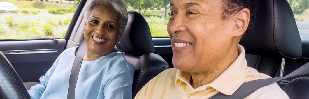 Two senior citizens in car smiling